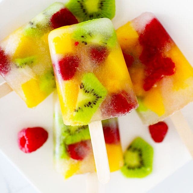 Colorful frozen popsicles with slices of real kiwi, peaches and raspberries
